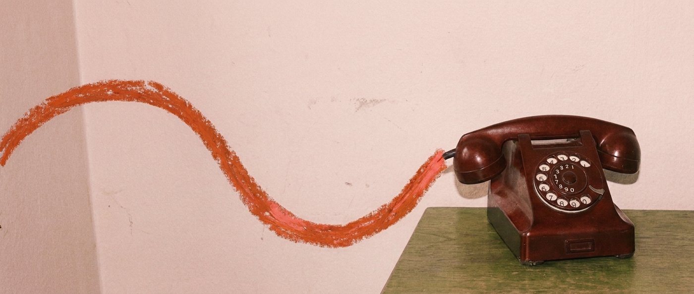 A rotary telephone with a crayon-drawn cord